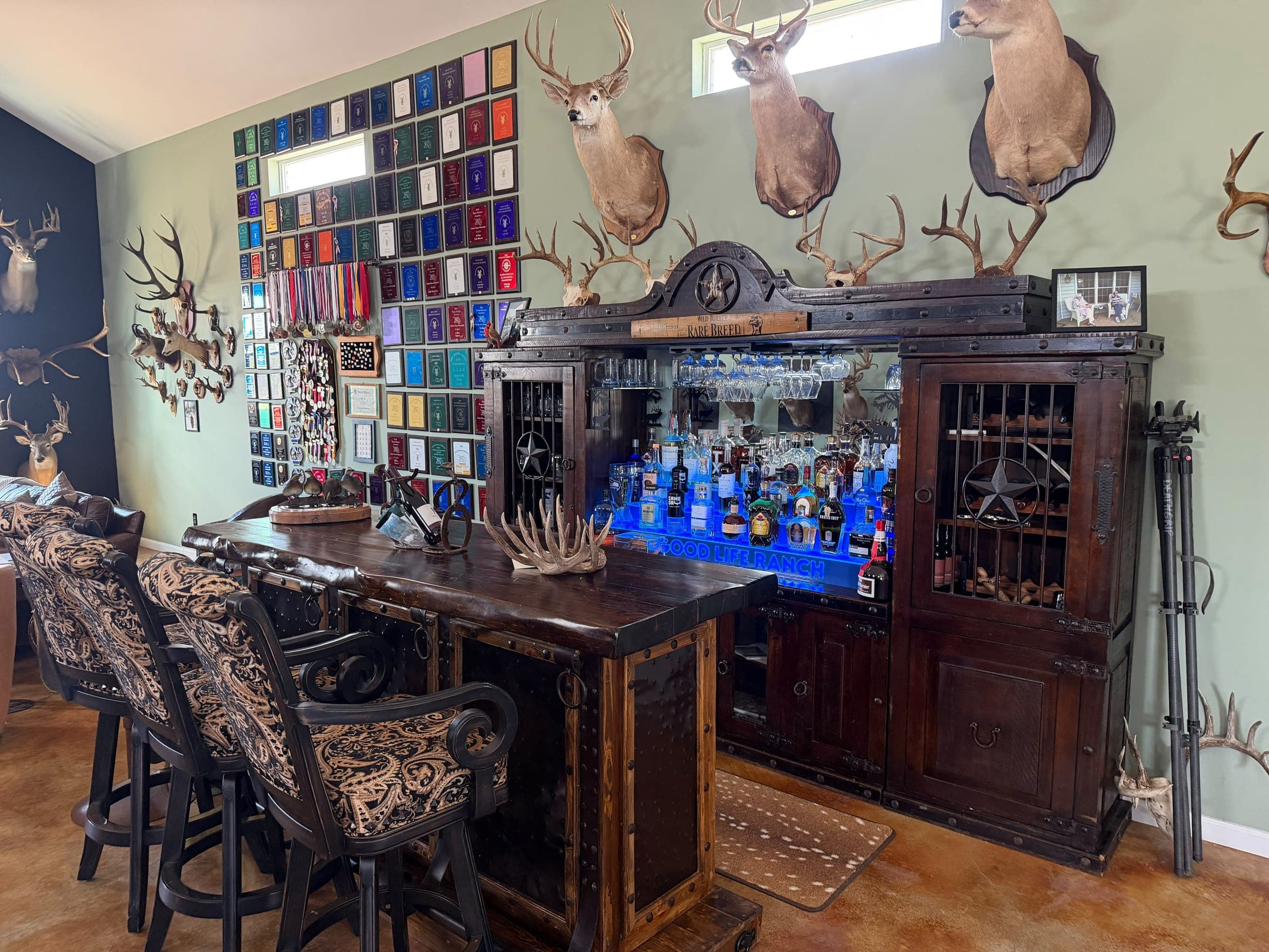 The lodge bar, backlit bottles on the shelves and mounted deer heads above it