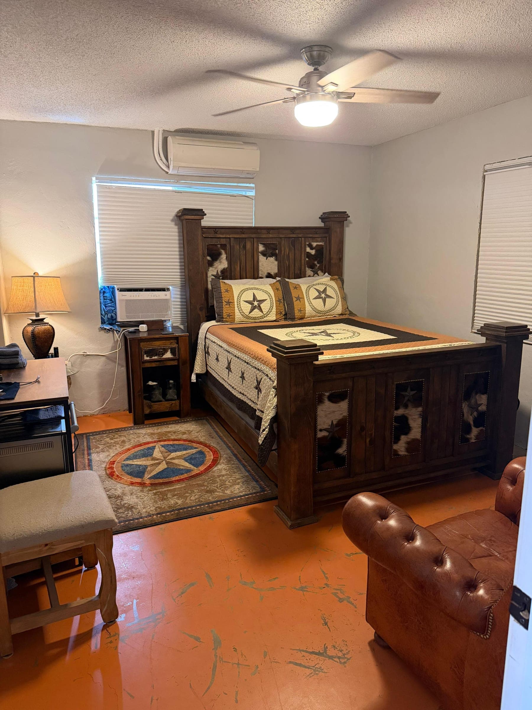 A lodge bedroom with a carved wooden bed, a Texas star quilt and a leather chair