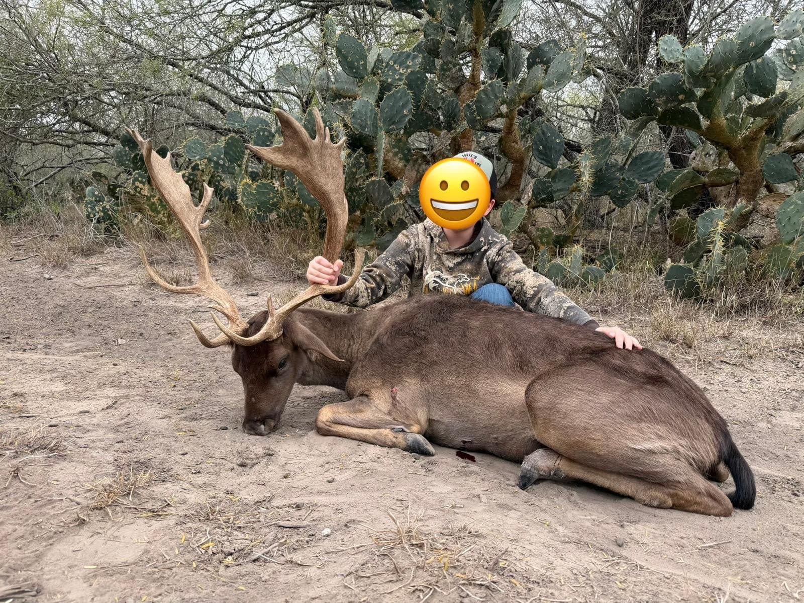 Young hunter seated behind a harvested fallow buck in dark winter coat