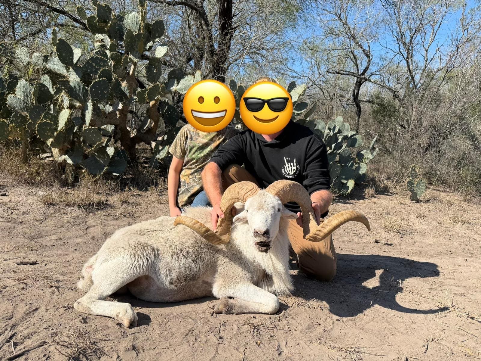 Adult and young hunter kneeling behind a harvested white ram