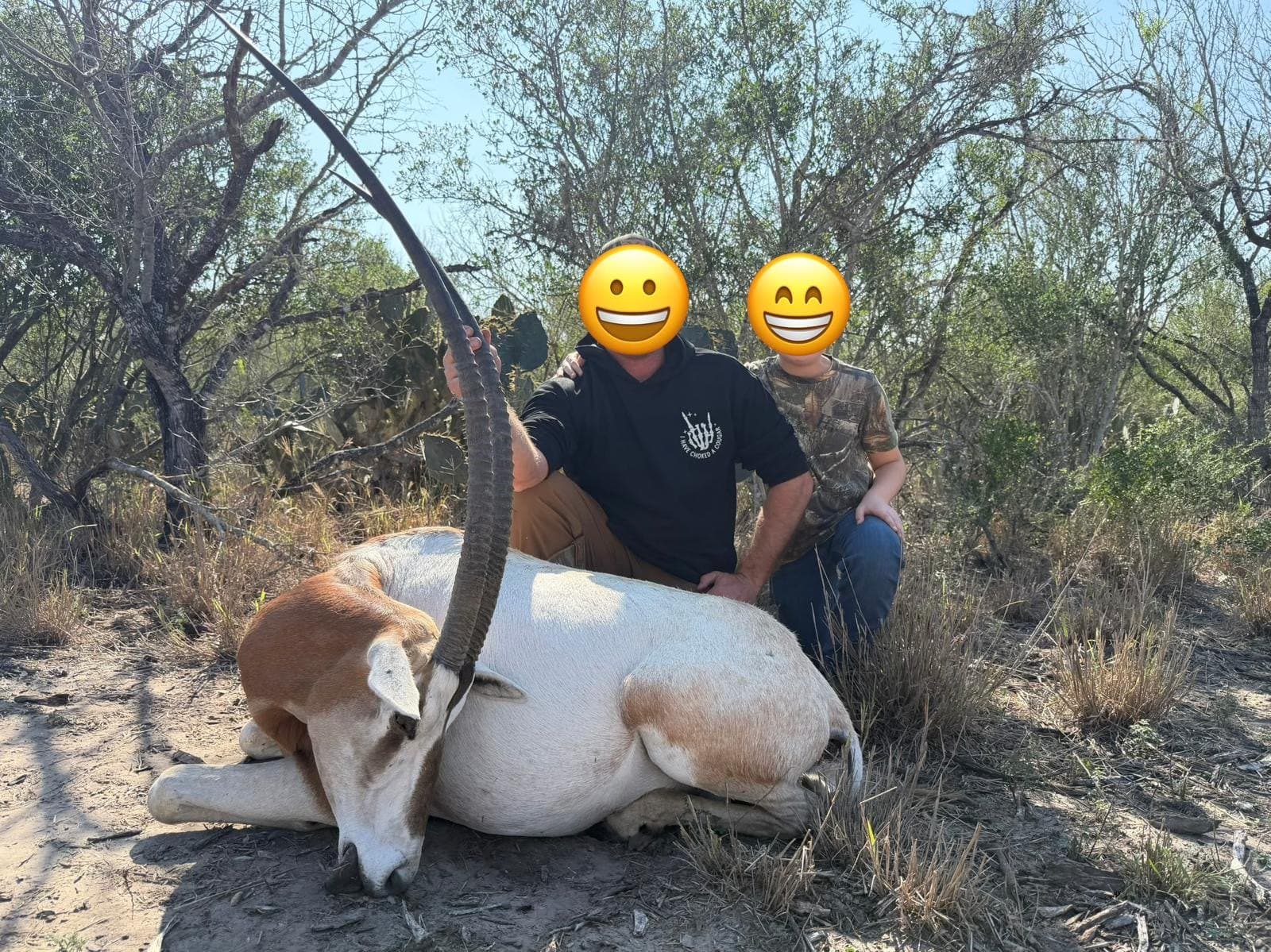 Adult and young hunter kneeling behind a harvested scimitar oryx