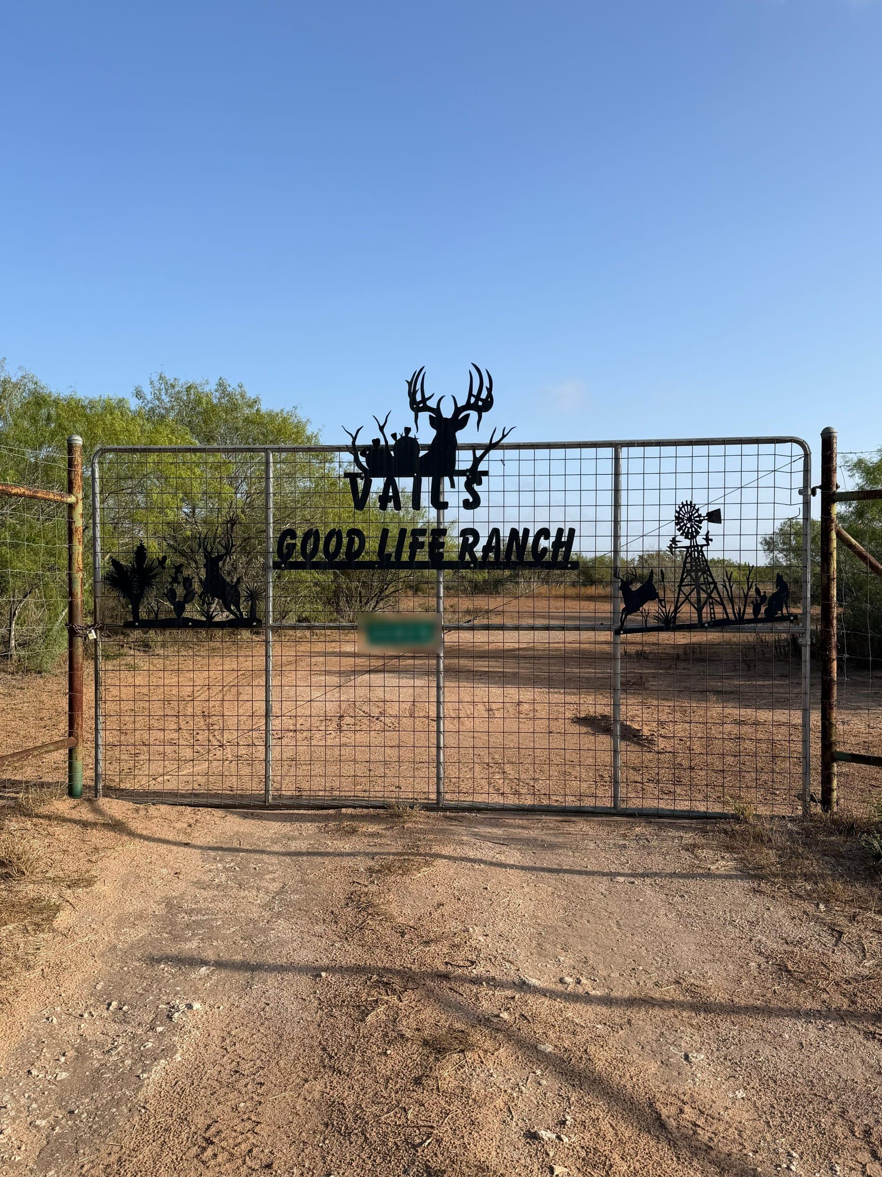 The ranch entrance gate, a Vail's Good Life Ranch sign across the top with metal cutouts of a buck, a windmill and wildlife